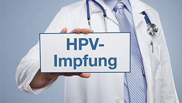 Arzt hält Schild in der Hand zur HPV-Impfung